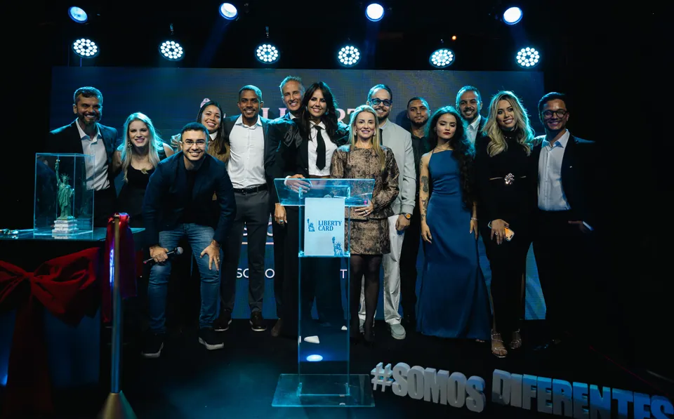 O time da Liberty Card reunido no palco do evento de inauguração, com a marca no telão ao fundo.