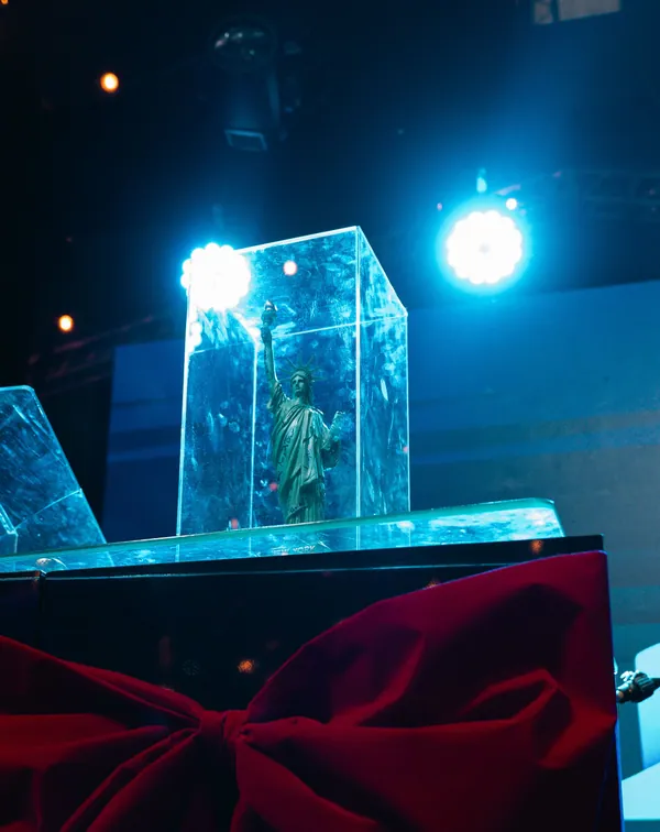Uma miniatura da Estátua da Liberdade dentro de uma caixa de acrílico iluminada, no palco do evento da Liberty Card.