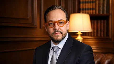 Retrato de Wesley Ribeiro, de terno e óculos, em um escritório.